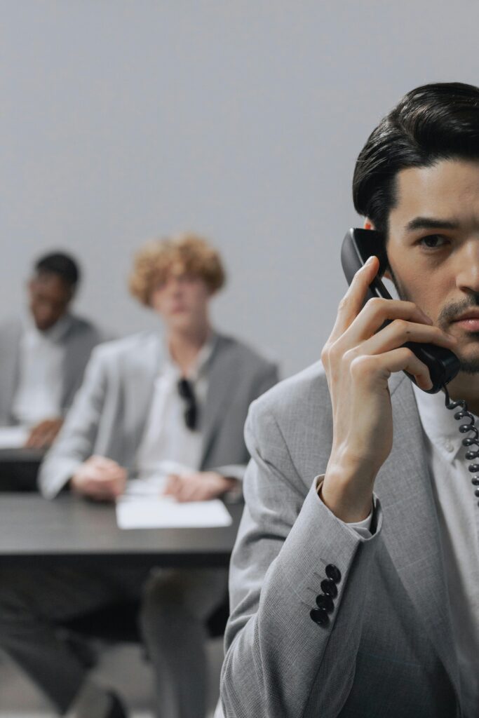 Τηλεφωνία Businessmen in a modern office setting engaged in a telephone conversation, showcasing teamwork.